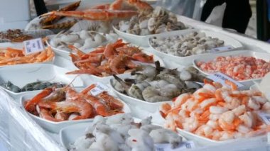 Marketin tezgahında çeşitli deniz ürünleri. Çeşitli karidesler, ahtapotlar, Almanca fiyat etiketli ıstakozlar.