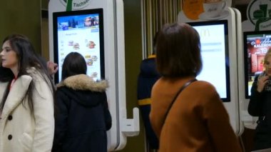 Viyana, Avusturya - 19 Aralık 2019: McDonalds 'da kasiyer olmayan siparişler için dijital ekran. İnsanlar dijital ekranla fast food siparişi veriyor. Operatörsüz modern teknolojiler