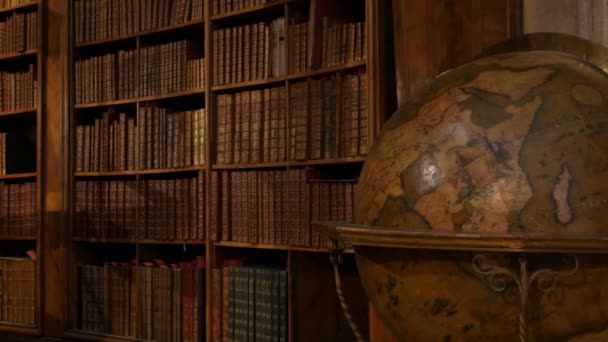 Alte große antike Weltkugel. Schöne alte Bücherregale mit namenlosen Büchern. Innenraum der Österreichischen Nationalbibliothek mit einer Reihe alter Bücher im Regal. — Stockvideo