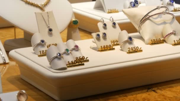 Ακριβά εκλεκτά κοσμήματα στον πάγκο του κοσμηματοπωλείου. Διάφορα διαμάντια, ζαφείρια, λευκόχρυσο σε σκουλαρίκια, βραχιόλια, δαχτυλίδια, κολιέ με price tags — Αρχείο Βίντεο