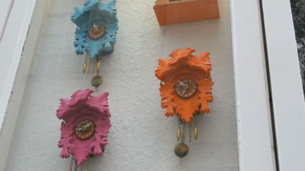 Разноцветные настенные часы с маятником в окне часового магазина — стоковое видео