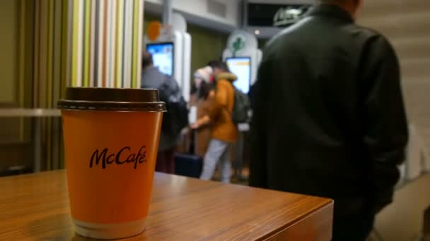 Bécs, Ausztria - 2019. december 19.: Egy pohár tejeskávé McDonaldwe-ban a pénztárgép nélküli megrendelések digitális képernyőinek hátterében — Stock videók