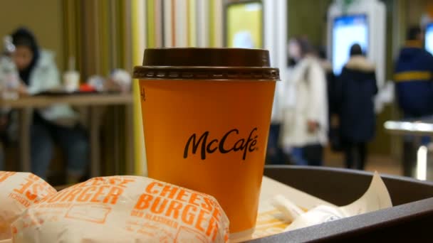 Viena, Austria - 19 decembrie 2019: Un pahar de cafea latte și o pereche de cheeseburgeri pe o tavă din McDonaldwe pe fundalul ecranelor digitale pentru comenzi fără casieri — Videoclip de stoc