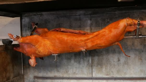 Grande porco no espeto. Carcaça de porco defumada e frita no mercado medieval de Natal em Munique. Porco assado inteiro cozido com fogo e carvão vegetal, comida de rua festiva da cozinha tradicional europeia — Vídeo de Stock