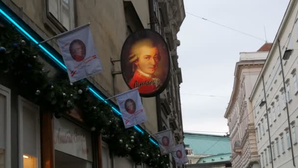 Вена, Австрия - 23 декабря 2019 года: Портрет всемирно известного композитора Вольфганга Амадея Моцарта на одном из зданий города. Символ Вены — стоковое видео
