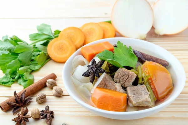 Ahşap zemin üzerine kabın içinde sığır eti ve sebze çorbası