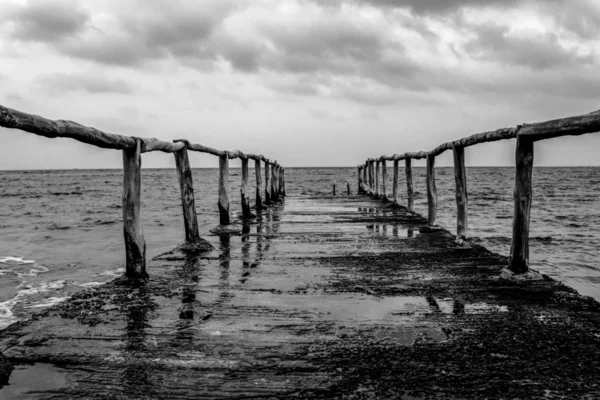 Perspektivvy av en pir på havsstranden med klart blå hav och dramatisk himmel — Stockfoto