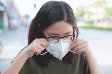 Toz PM2.5 / hava çekimini önlemek ya da korumak için beyaz yüz maskesi takan Asyalı kadın