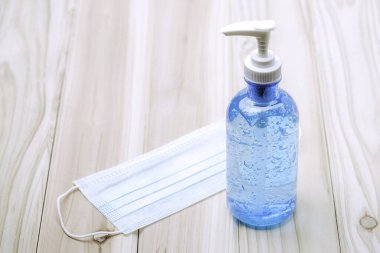 El dezenfektanı şişesi ya da alkol jeli ve ameliyat maskesiyle ahşap masa üzerinde cpoy spcae