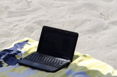 Bir dizüstü bilgisayar üzerinde plaja havlu konuyor
