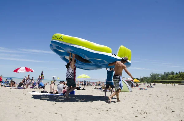 Personnes non identifiées sur la plage avec un énorme lit flottant du lac Grand Bend en été dans un ciel bleu profond — Photo