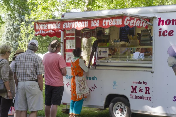 Des personnes non identifiées attendent en ligne pour acheter de la crème glacée sur le stand du parc lors d'un festival champêtre — Photo