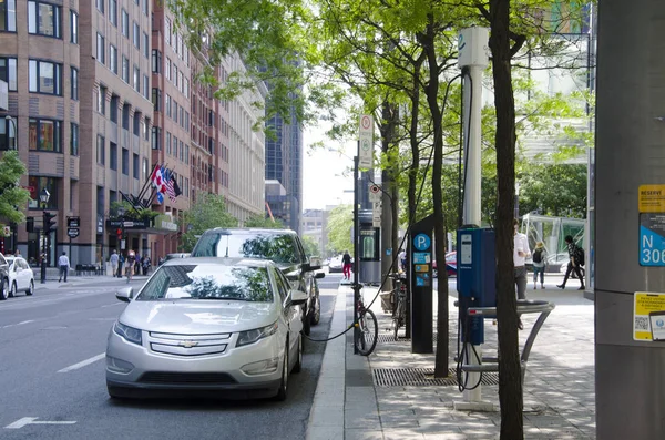 Chargement de voiture électrique à la station de recharge dans la rue sous les arbres verts en été — Photo