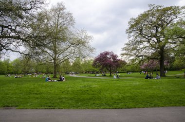 Londra, Ingiltere. 22 Nisan 2018. İnsanlar bir bulutlu par dinlenmek almak