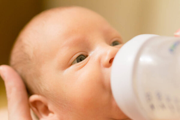 Cute newborn baby drinking milk from a bottle. Stock photo