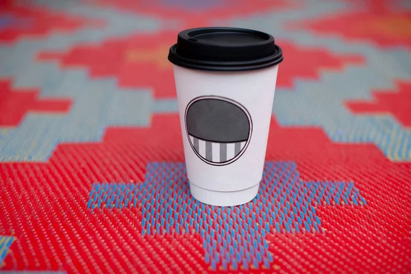 White paper cup for drinks (coffee or tea) standing on a bright colored background.