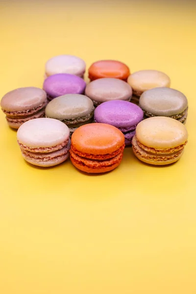 Colorful macaroons cake isolated on the yellow background. Close-up. Concept of sweet food.