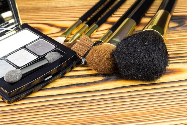 Cepillos cosméticos profesionales para maquillaje sobre fondo de madera . — Foto de Stock