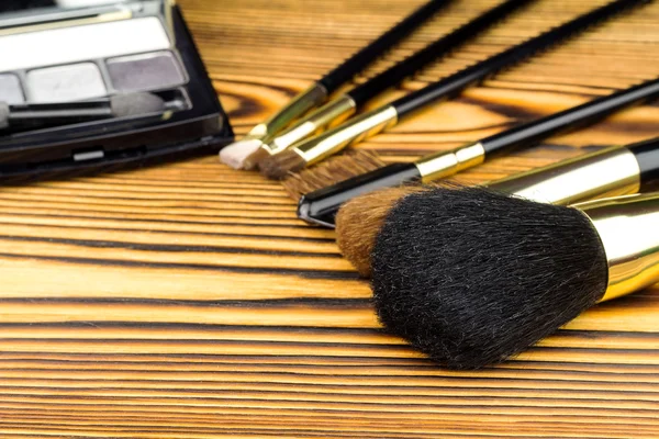 Cepillos cosméticos profesionales para maquillaje sobre fondo de madera . — Foto de Stock