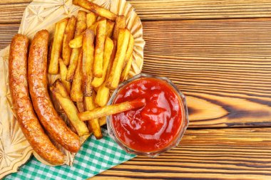 Homemade fast food, portion of french fries, ketchup, grilled sausages on wooden board. clipart