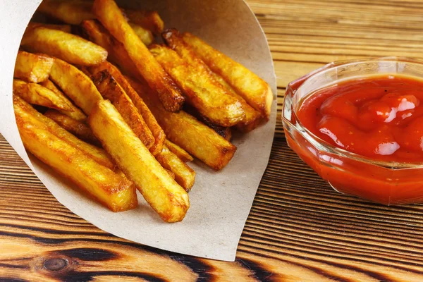 Hemmagjord snabbmat portion pommes frites i papperspåse på trä bord — Stockfoto