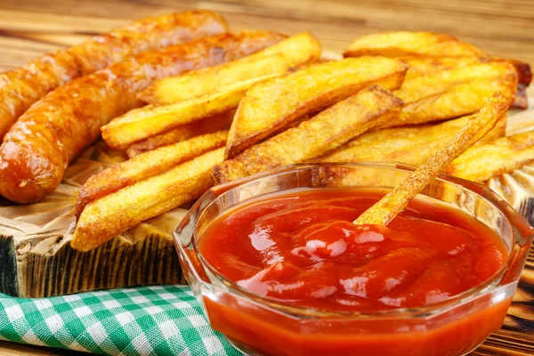 Hemmagjord snabbmat, portion pommes frites, ketchup, grillad korv, trä ombord. — Stockfoto