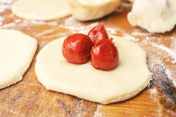 Préparation de boulettes ukrainiennes maison ou varenyky, couper les morceaux ronds de pâte à la cerise — Photo