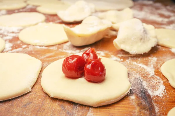 Préparation de boulettes ukrainiennes maison ou varenyky, couper les morceaux ronds de pâte à la cerise — Photo