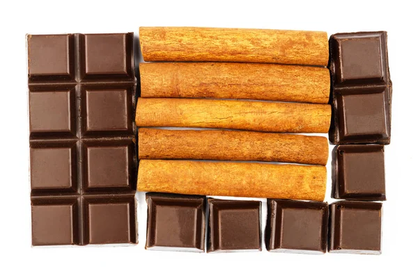 Mörk chokladkaka och kanel pinnar isolerade på vit bakgrund, ovanifrån. — Stockfoto