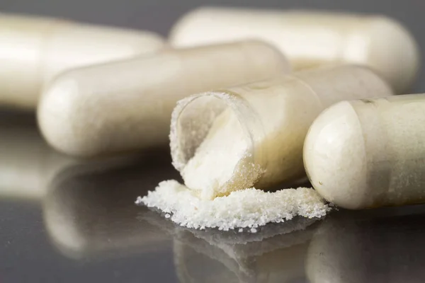 Glucosamine kapsül kesmek, gıda ek hapları görüntüyü parlak koyu arka plan üzerinde.