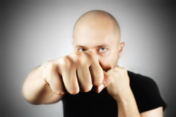 Punch with clenched fist of a young bald man.