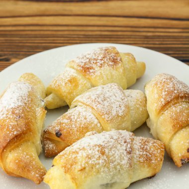 Ahşap arka plan üzerinde beyaz tabak içinde ev yapımı taze simit.