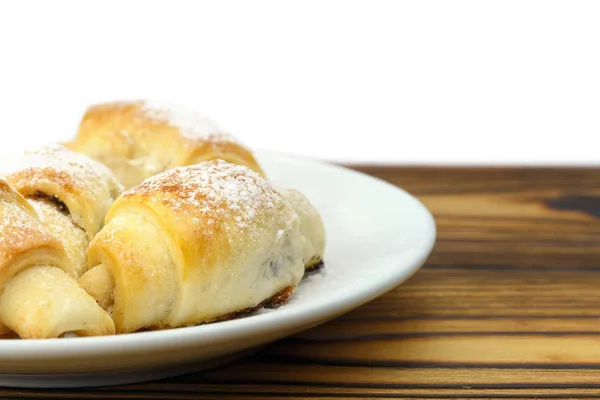 Panecillos frescos hechos en casa en plato sobre fondo de madera y blanco . — Foto de Stock