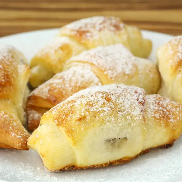 Ahşap arka plan üzerinde beyaz tabak içinde ev yapımı taze simit.