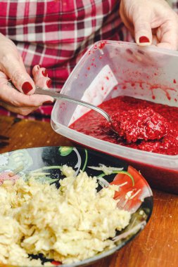 Kadın el plaka içinde bir rendelenmiş elma ahududu reçel dökmek.