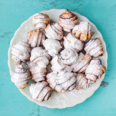Ev yapımı taze kurabiye silkeledi şekere de beyaz plaka üzerinde ahşap mavi arka plan, üstten görünüm.