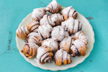 Ev yapımı taze kurabiye silkeledi pudra şekeri ahşap mavi zemin üzerine beyaz plaka.