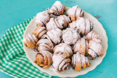 Ev yapımı taze kurabiye silkeledi şekere de beyaz tabakta ahşap mavi arka plan ve peçete.
