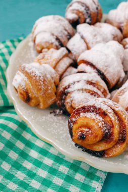 Ev yapımı taze kurabiye silkeledi şekere de beyaz tabakta ahşap mavi arka plan ve peçete.