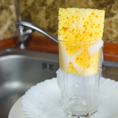 Mutfaktaki lavaboda bulaşık yıkamak için köpüklü sünger.