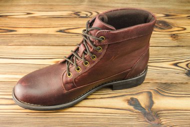 Ahşap arka plandaki erkekler için şık kahverengi deri çizmeler.