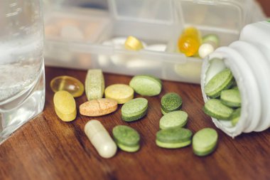 Tahta masada ve şişede doğal gıda takviyesi ve vitamin hapları var.