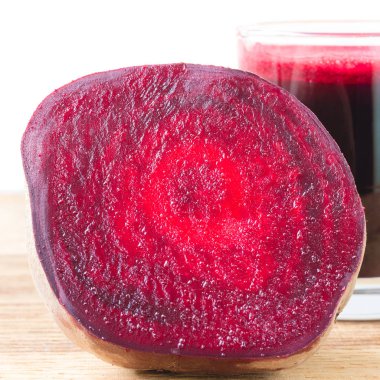 Yarım pancar kökü ve taze pancar suyunu tahta masada, beyaz arka planda cam ile kes.