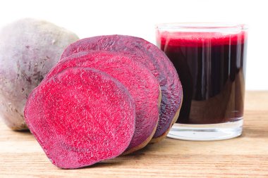 Yarım pancar kökü ve taze pancar suyunu tahta masada, beyaz arka planda cam ile kes.