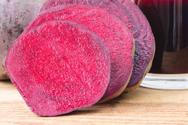 Yarım pancar kökü ve taze pancar suyunu ahşap masada cam ile kes.