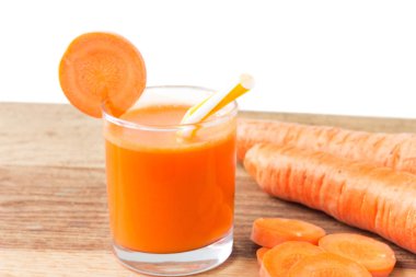 Bardakta taze havuç suyu, saman ve ahşap masa üzerinde havuç ve beyaz arka plan.