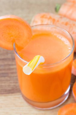 Bardakta taze havuç suyu, saman ve ahşap masada havuç.