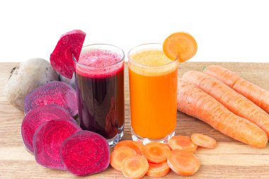 İki bardak taze pancar ve havuç suyu, pancar kökü ve havuç, ahşap masada sebze, beyaz arka plan.