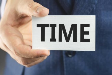 Mavi takım elbiseli bir iş adamı, yakın çekimde mesaj zamanı gösteren bir kart.