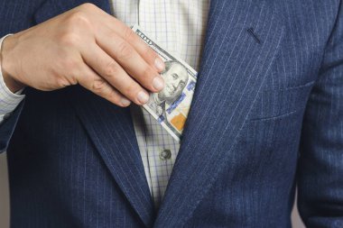 İş adamı cebine 100 dolar para koydu, rüşvet konsepti.